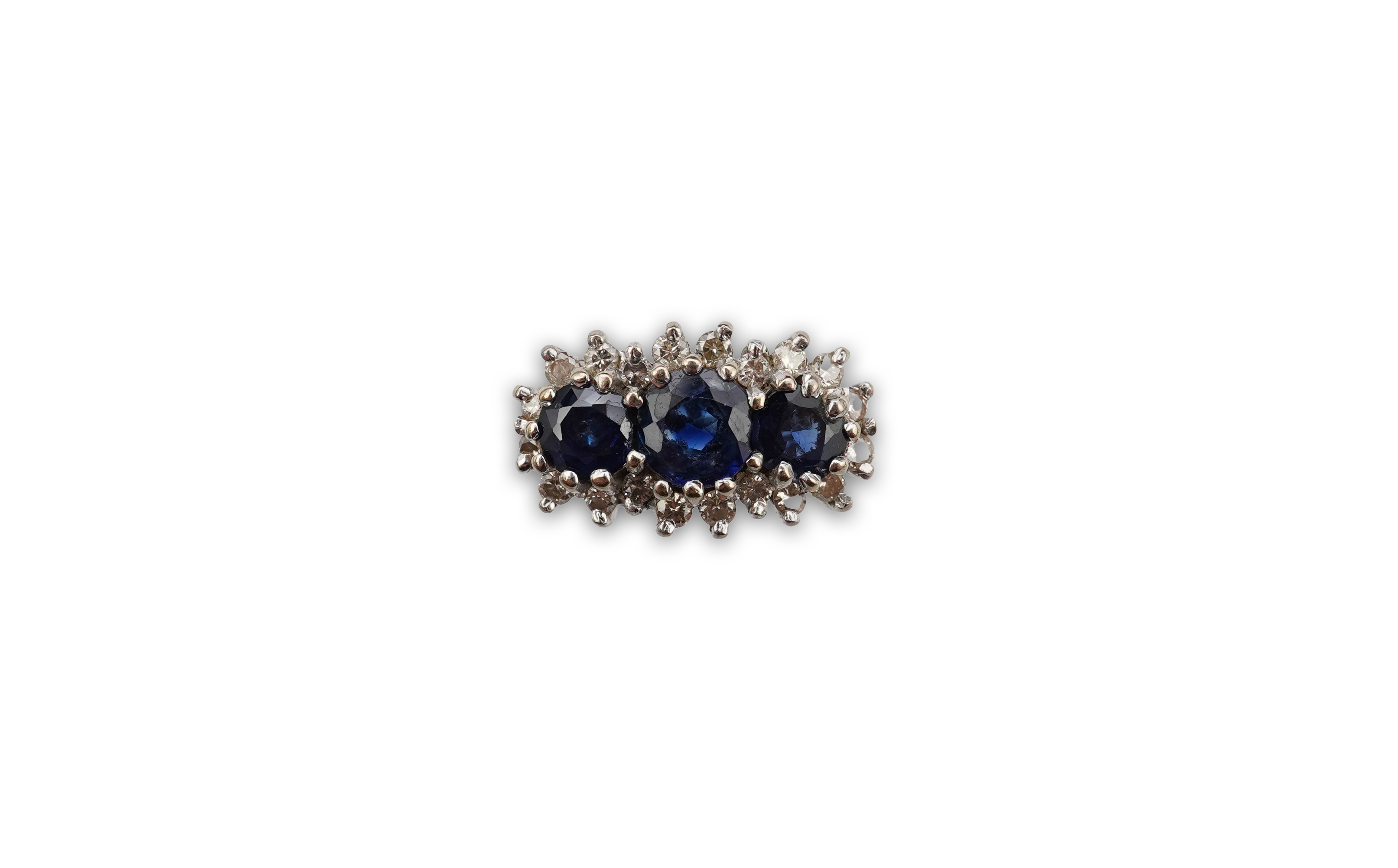 A sapphire and diamond ring, set with three circular-cut and oval sapphires, within a border of brilliant-cut diamonds totalling approximately 0.40 carats, mounted in 18ct white gold, size M1/2, British hallmarks, gross